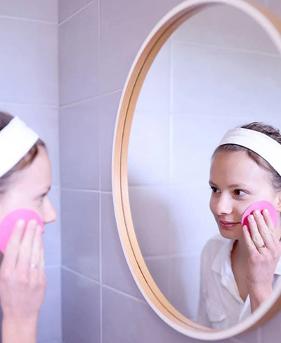 Une jeune femme qui se démaquille devant le miroir.
